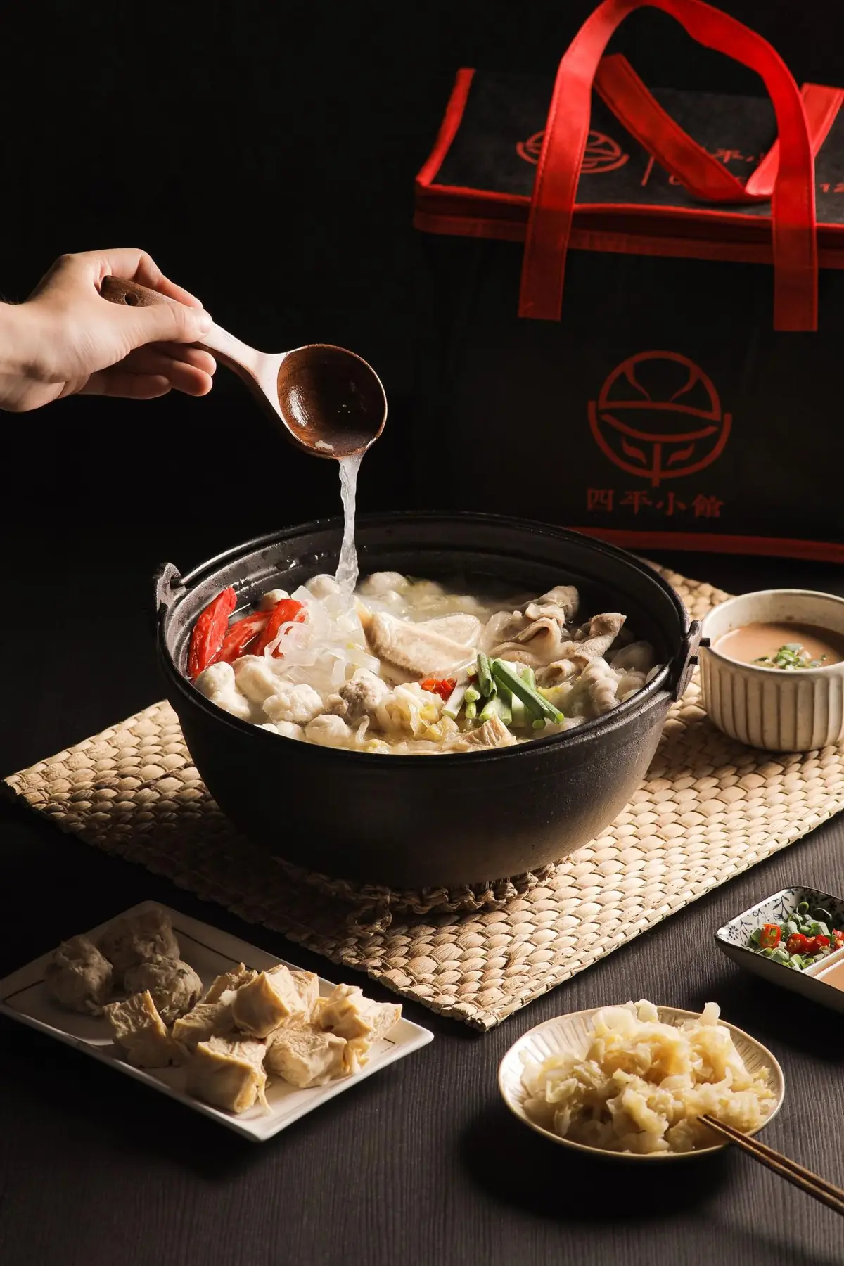 木杓把湯底倒進一鍋酸菜白肉鍋,後方是四平小館保冰袋